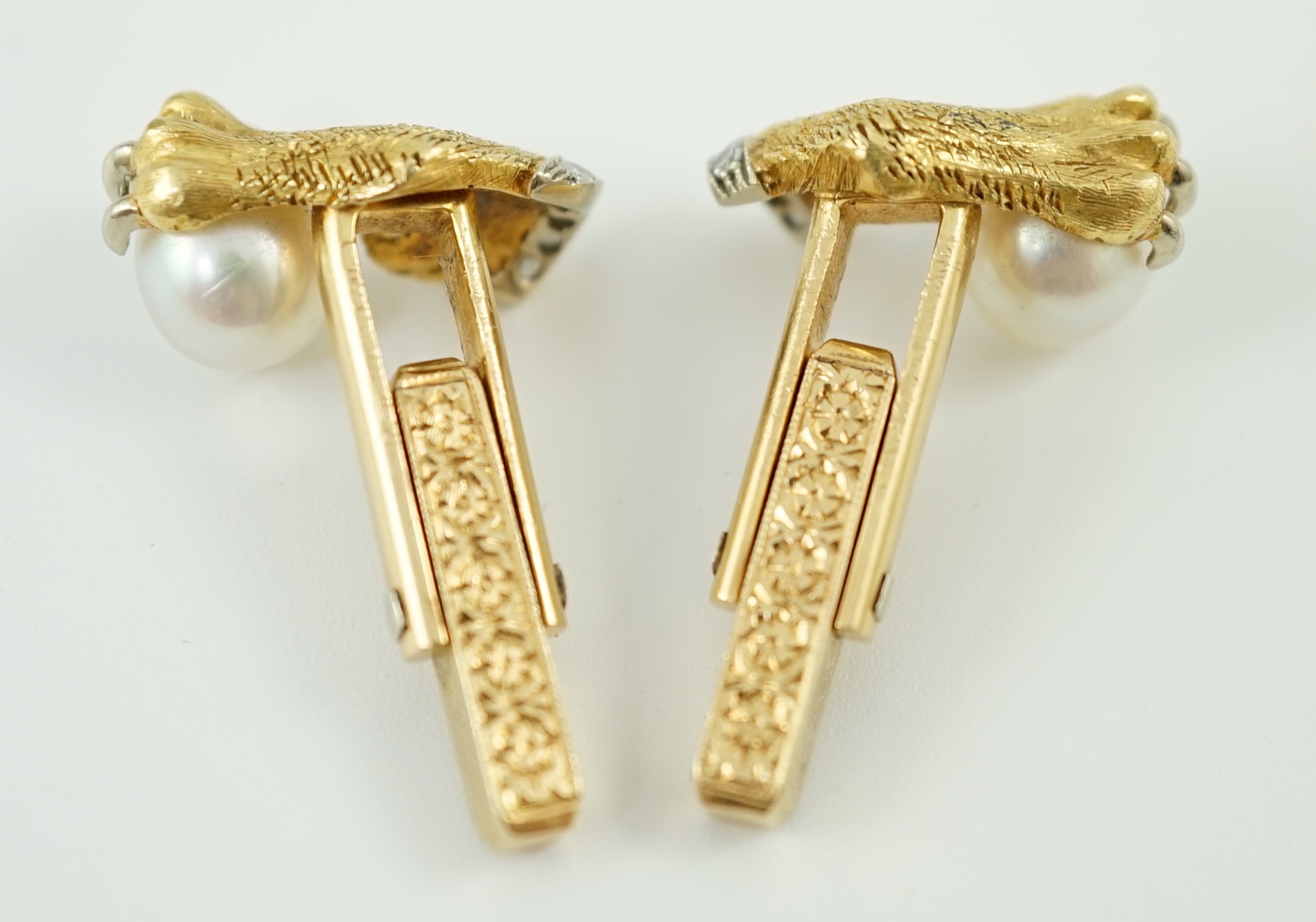 A mid 20th century pair of engraved and textured gold and platinum, diamond chip and cultured pearl cufflinks, each modelled as a lion's paw